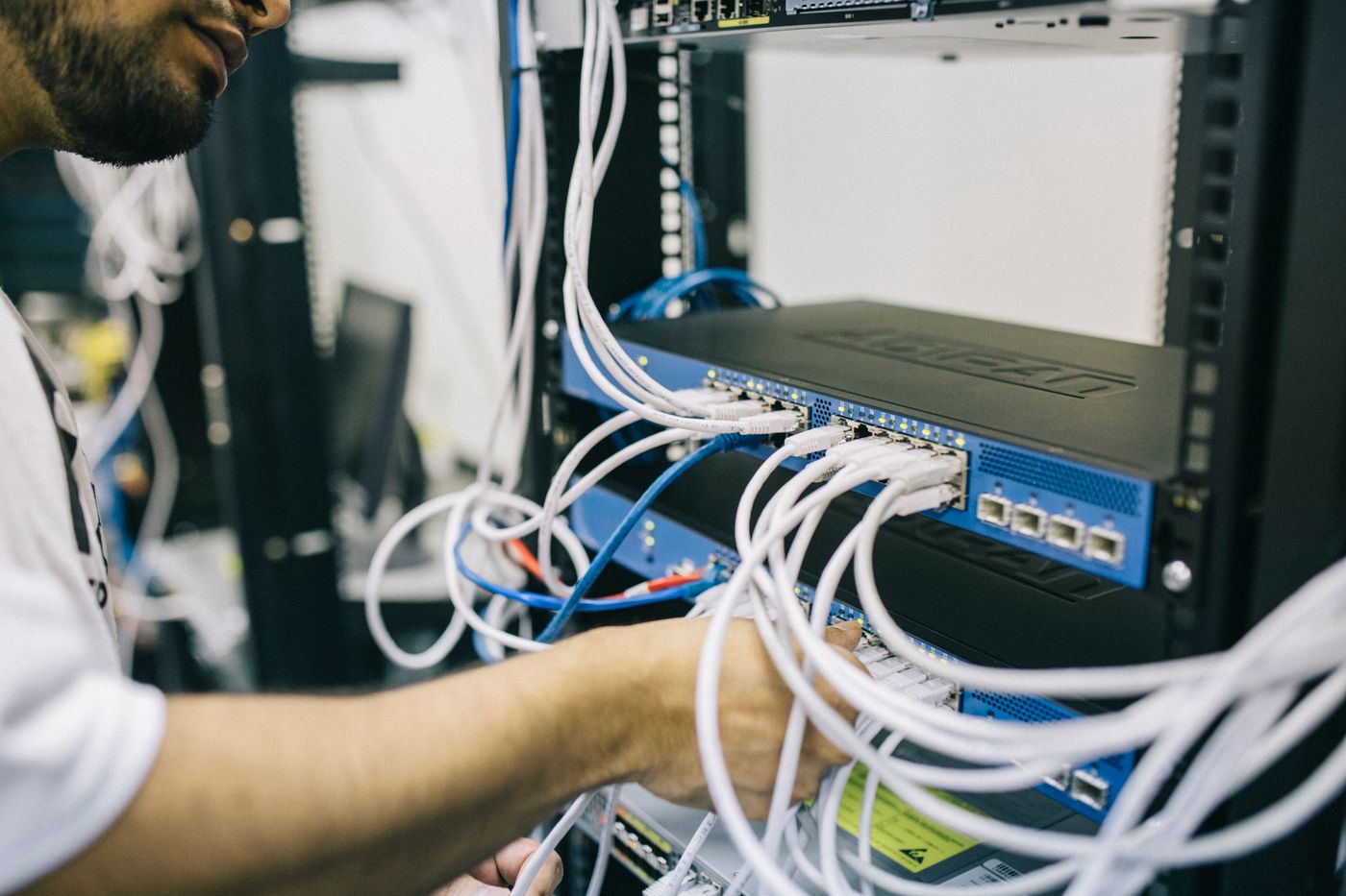 Technician connecting Ethernet cables in a network equipment rack
